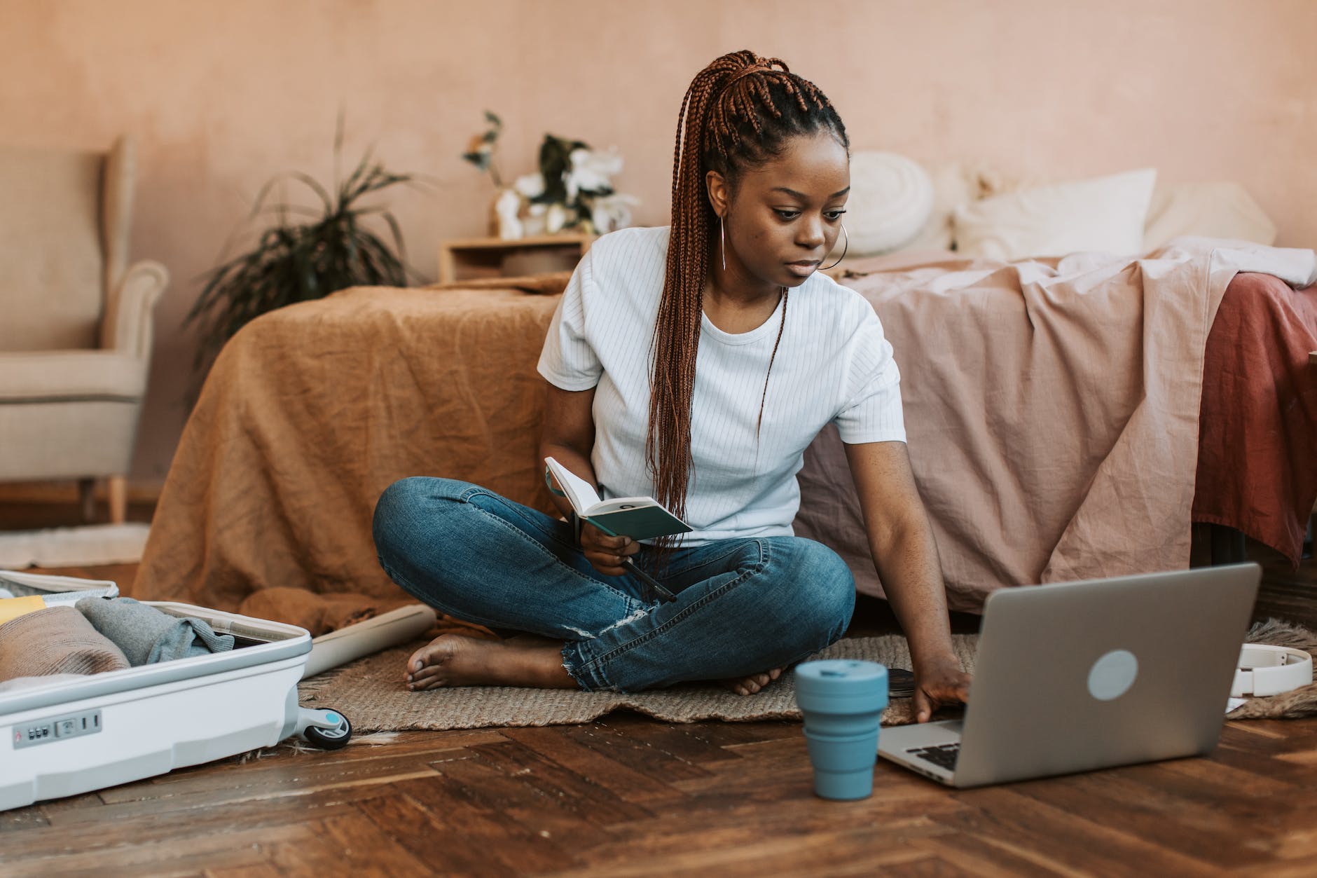 woman with long brown braided hair using laptop on floor