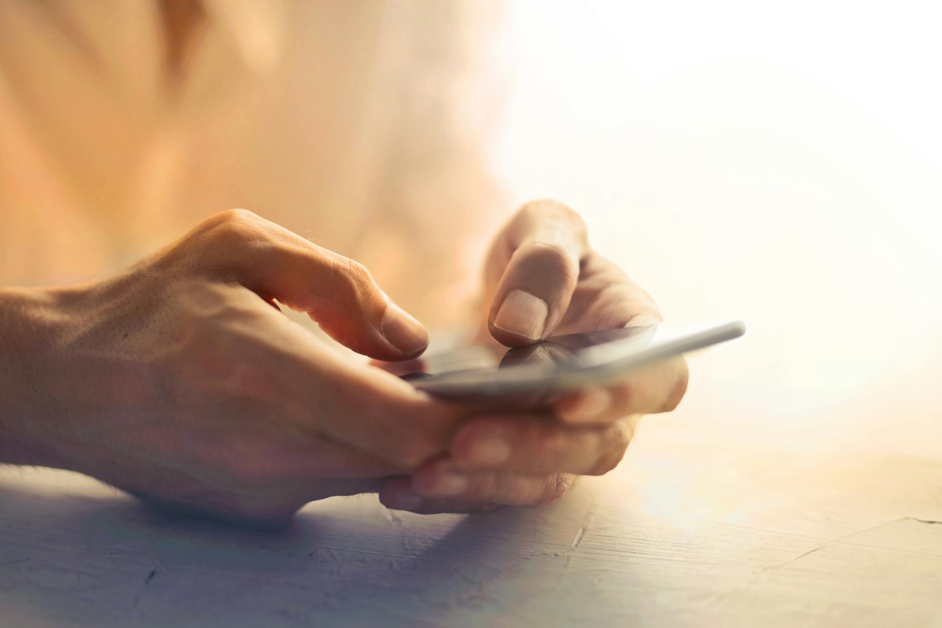 person holding white smartphone on white table looking for emergency loans