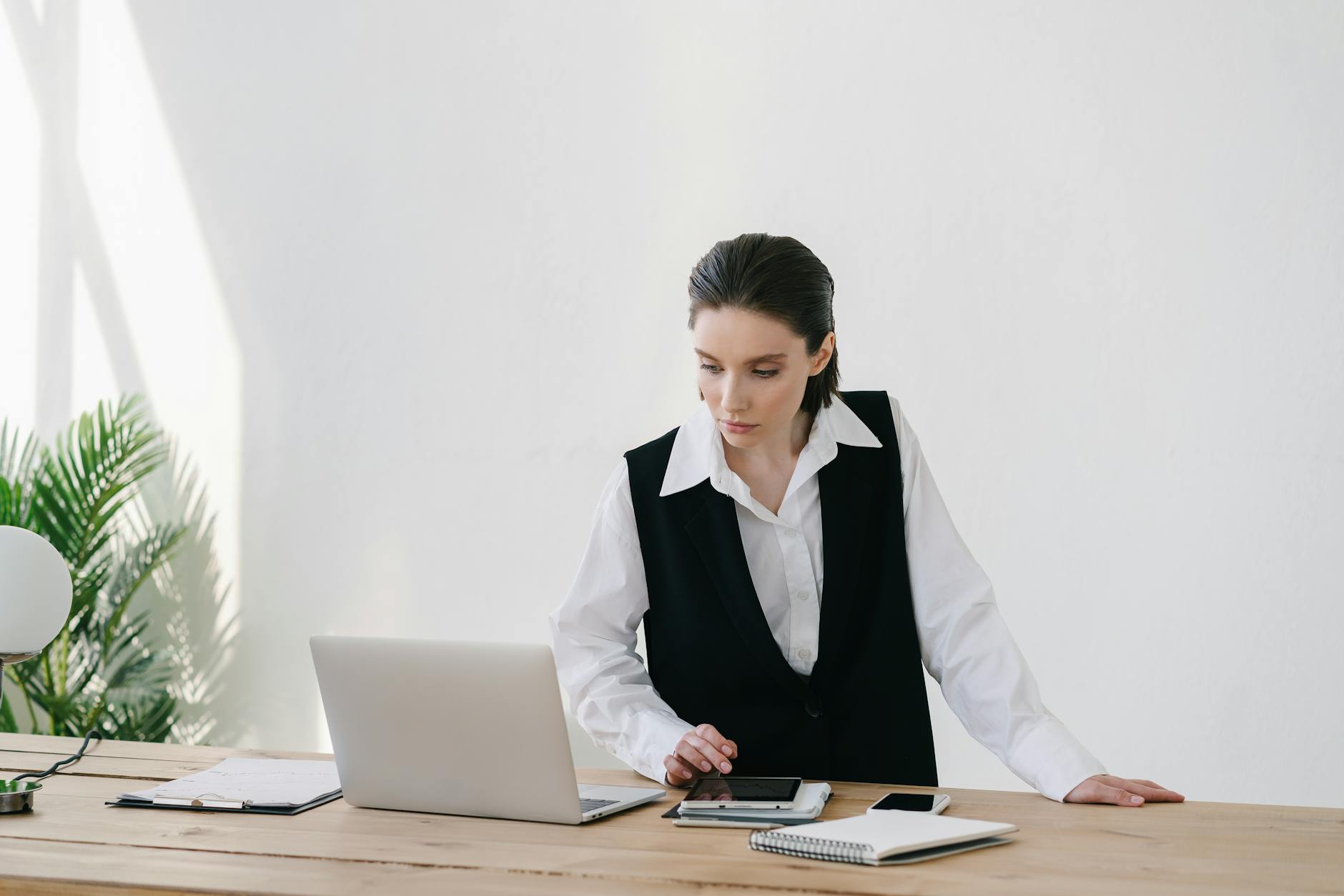 woman standing at wooden table working looking at laptop screen for urgent cash loan